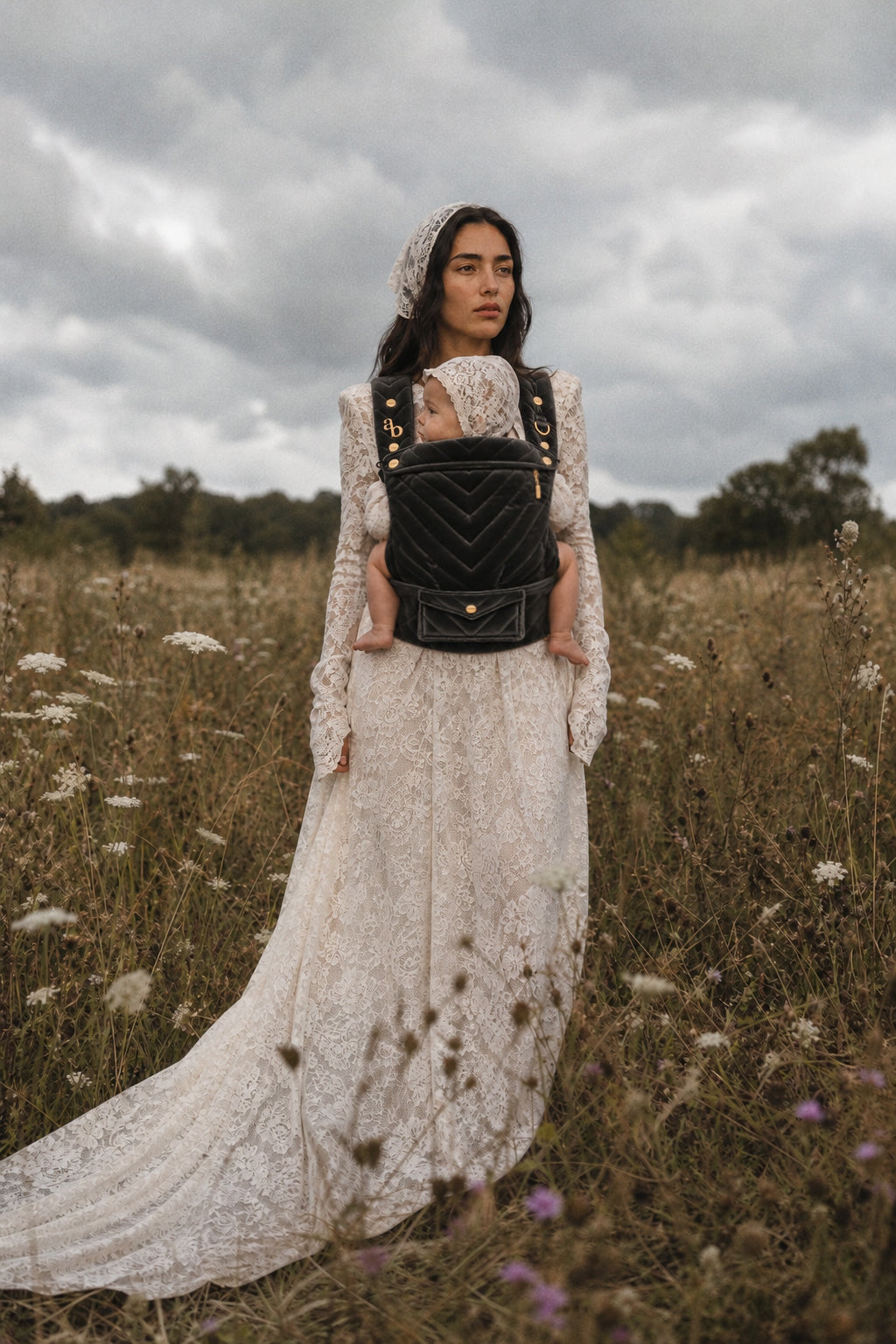 Mother wearing an Ariblake baby carrier in a wildflower field